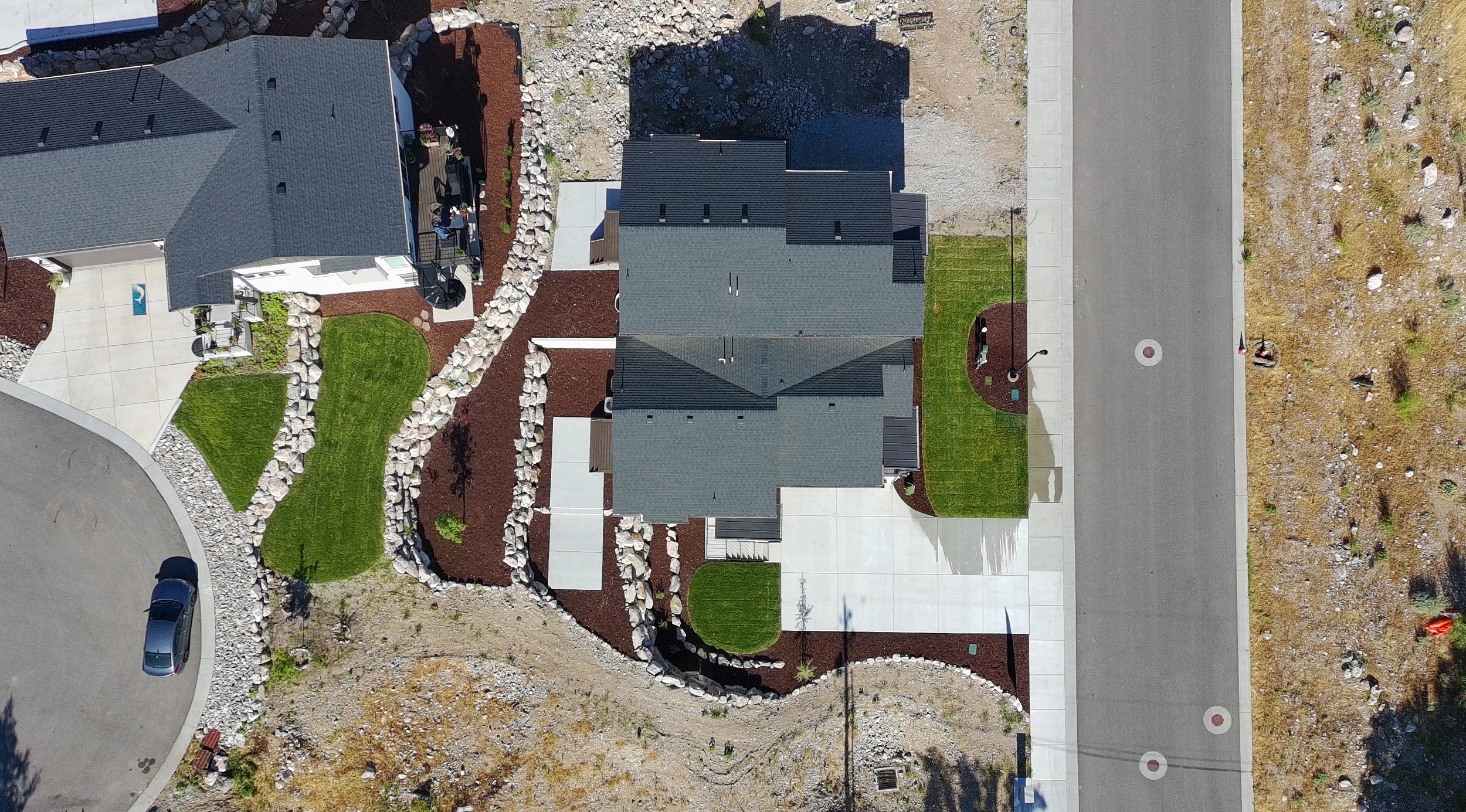 Modern residence with a dark shingle roof, concrete driveway, and manicured lawns