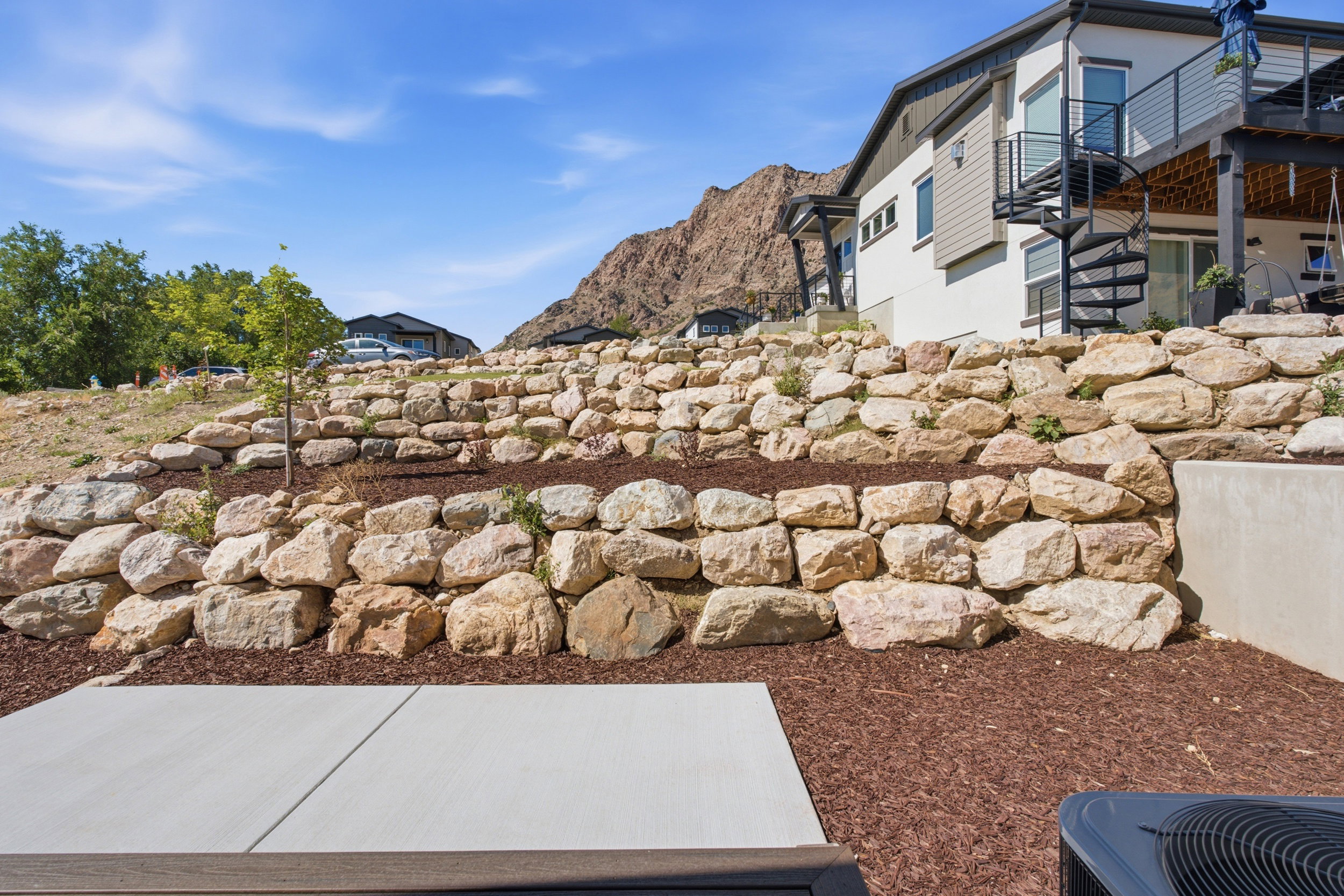 Terraced rock landscaping with natural stone retaining walls and mulched beds