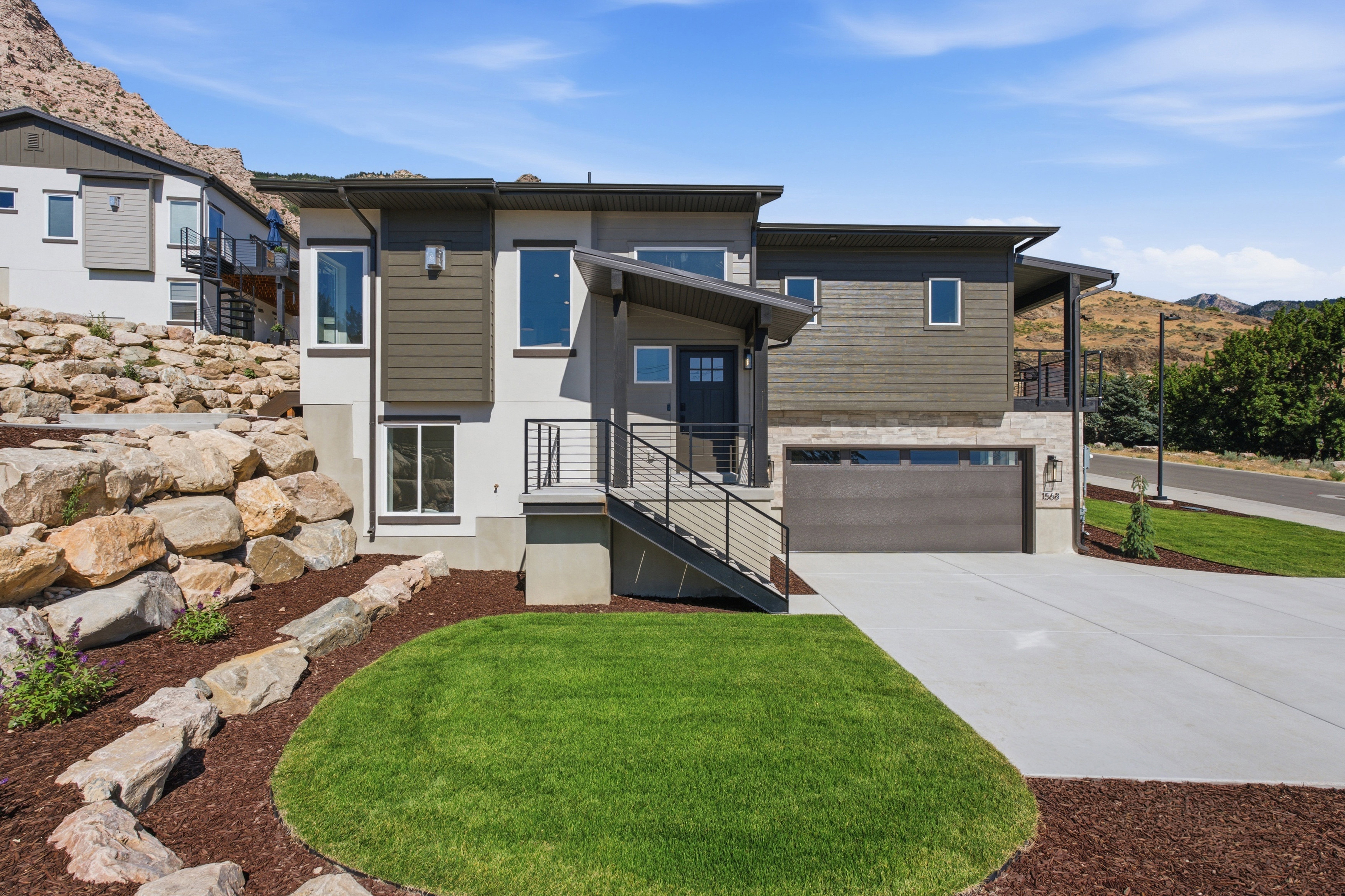 Contemporary multi-level residence featuring a gray exterior, stone accents, and dark wood-finish siding
