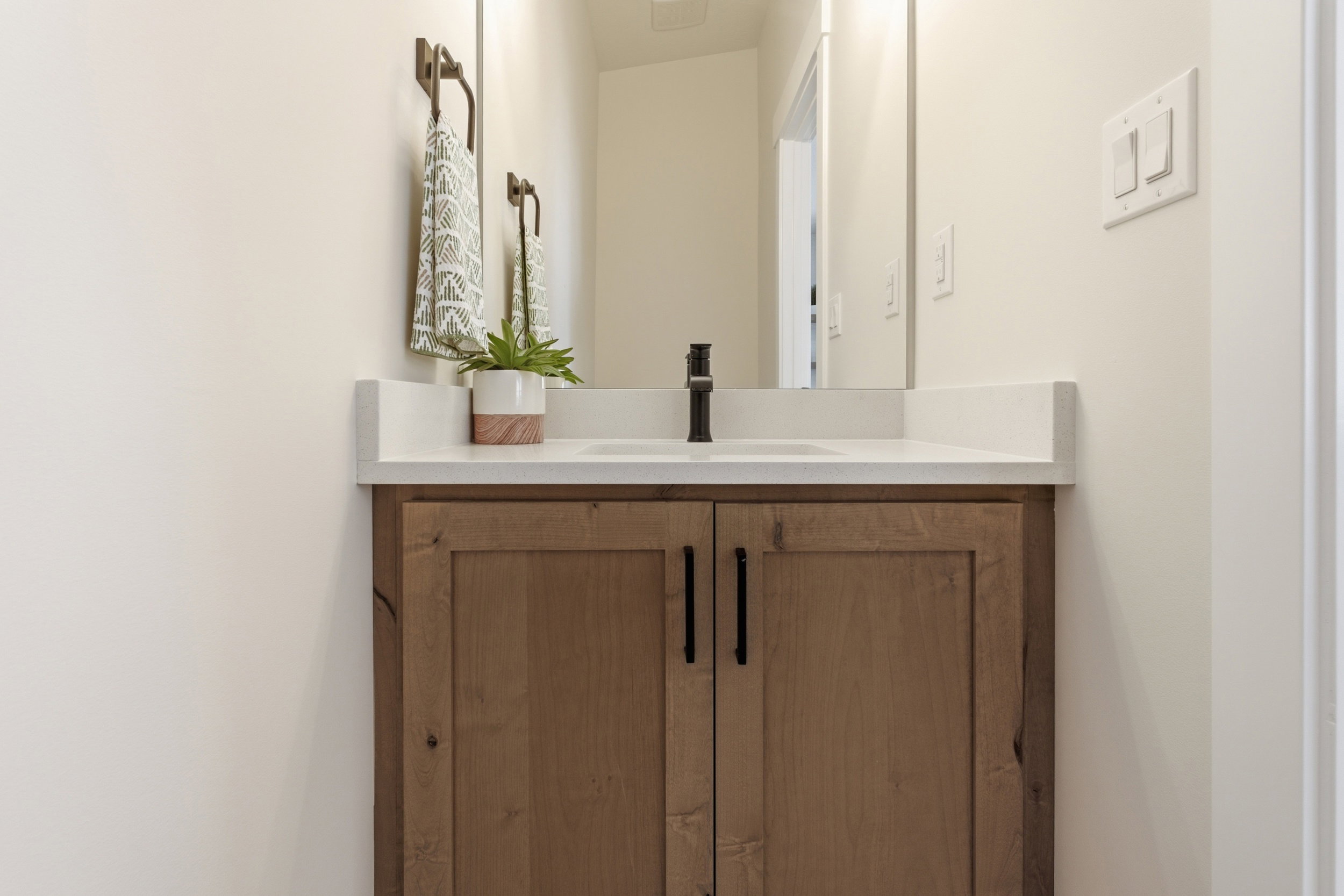 Wood-finish vanity with black hardware, white countertop, and integrated sink