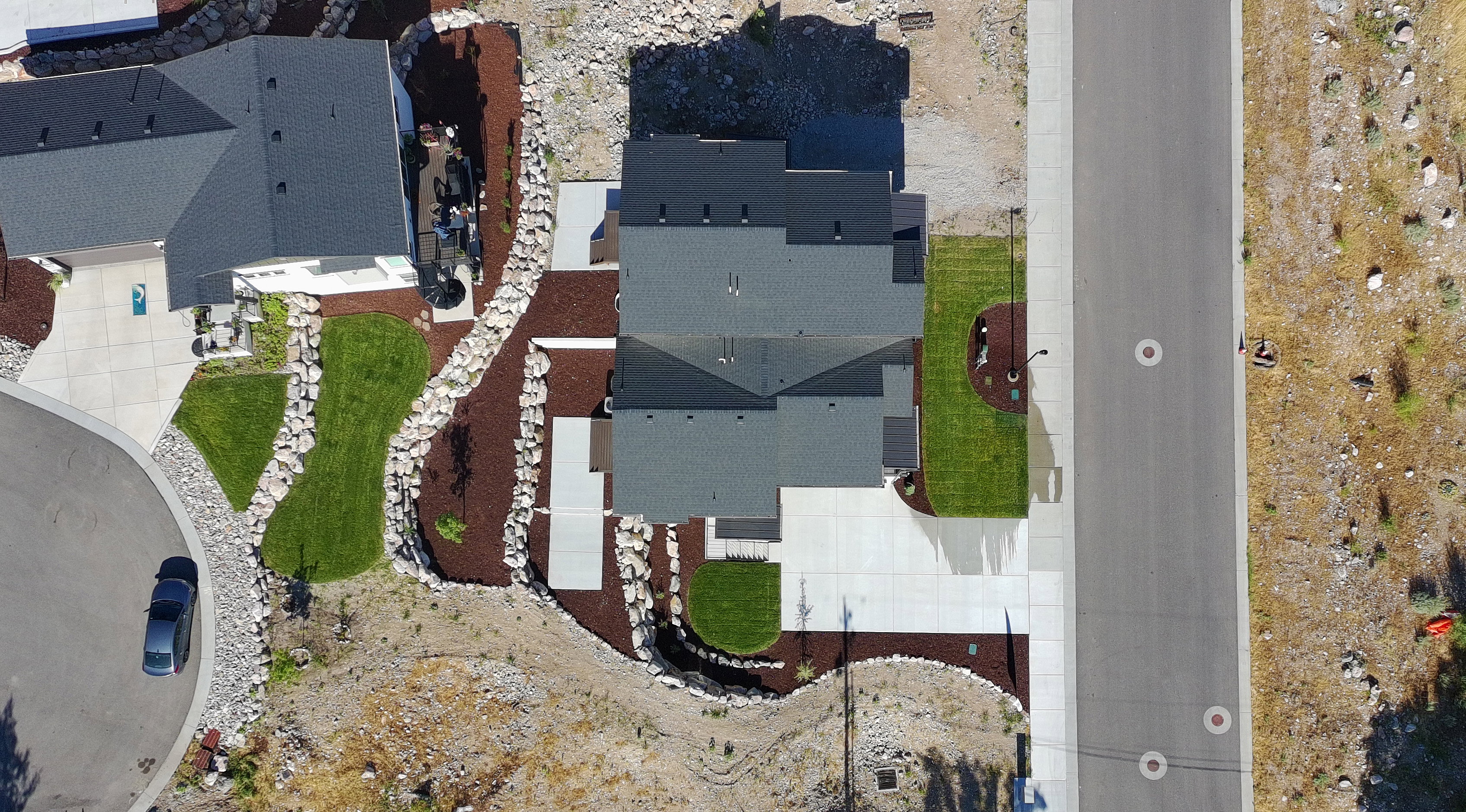 Aerial view of a contemporary property featuring a dark shingle roof and concrete driveway