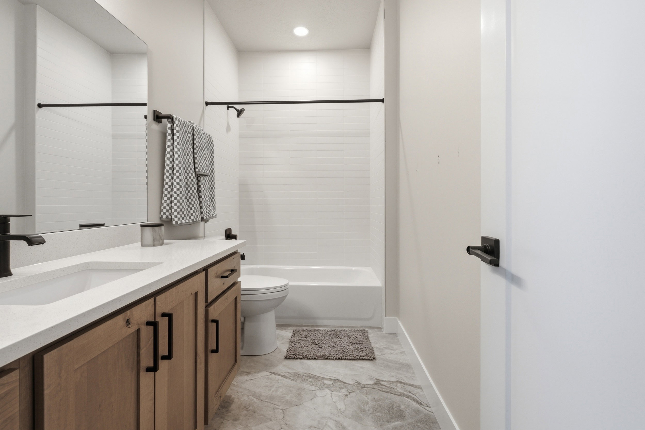 Bathroom featuring a wood-finish vanity with a light-colored countertop, integrated sink, and matte black fixtures