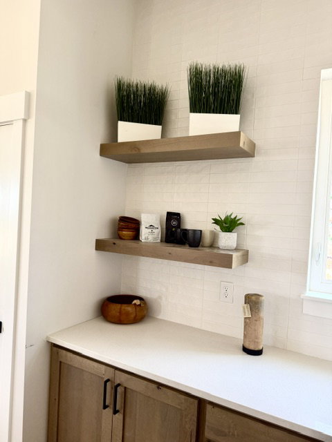 White tile backsplash with two floating wood-finish shelves