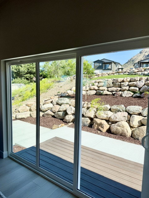 Sliding glass door opening to a private patio and tiered rock landscaping