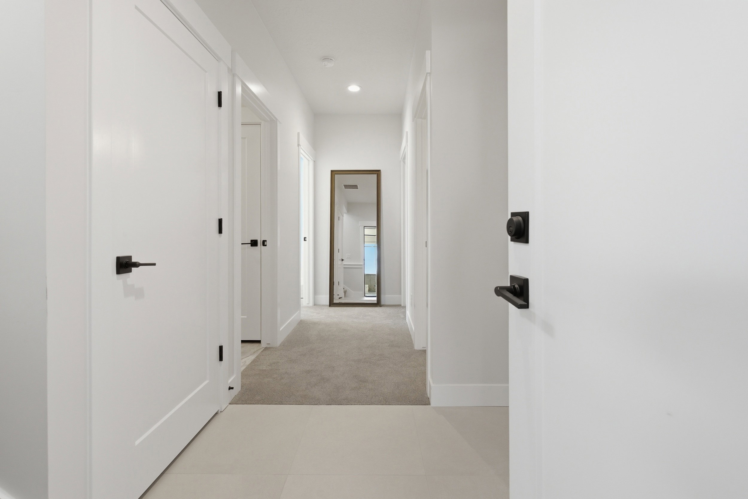 Bright hallway featuring light tile flooring and plush carpeting