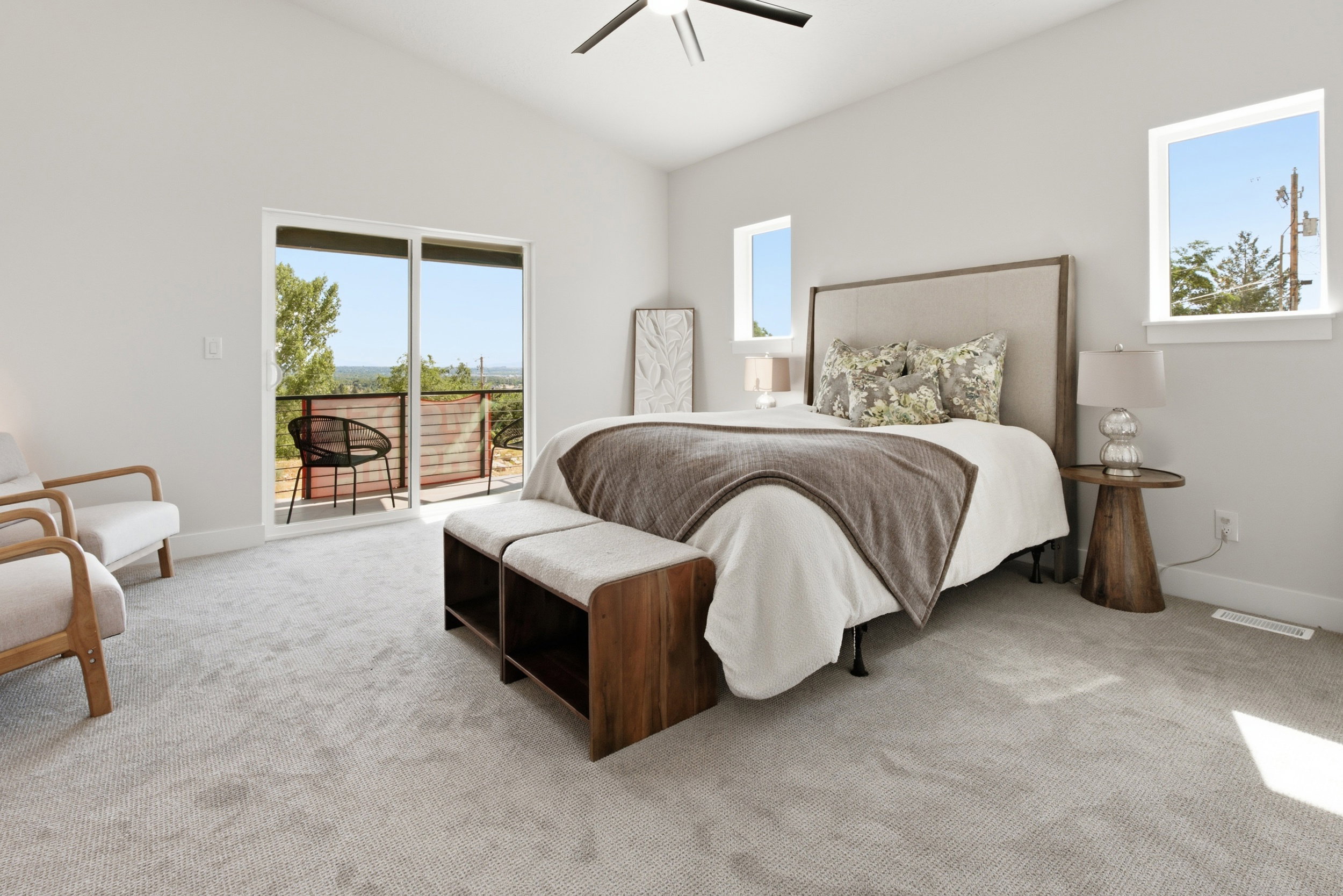 Light-filled bedroom featuring a vaulted ceiling, sliding glass door access to an exterior balcony, and multiple windows