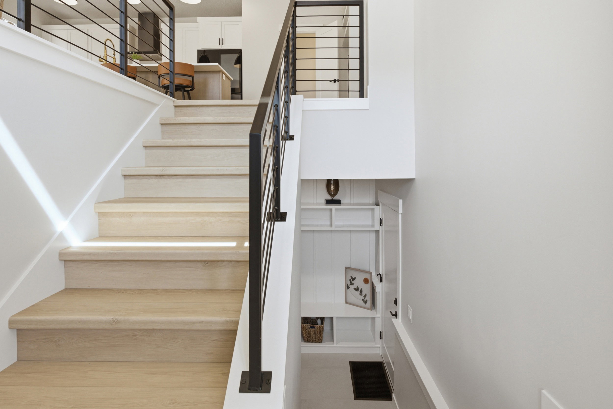 Staircase featuring wood-finish treads and risers with a contemporary black metal railing