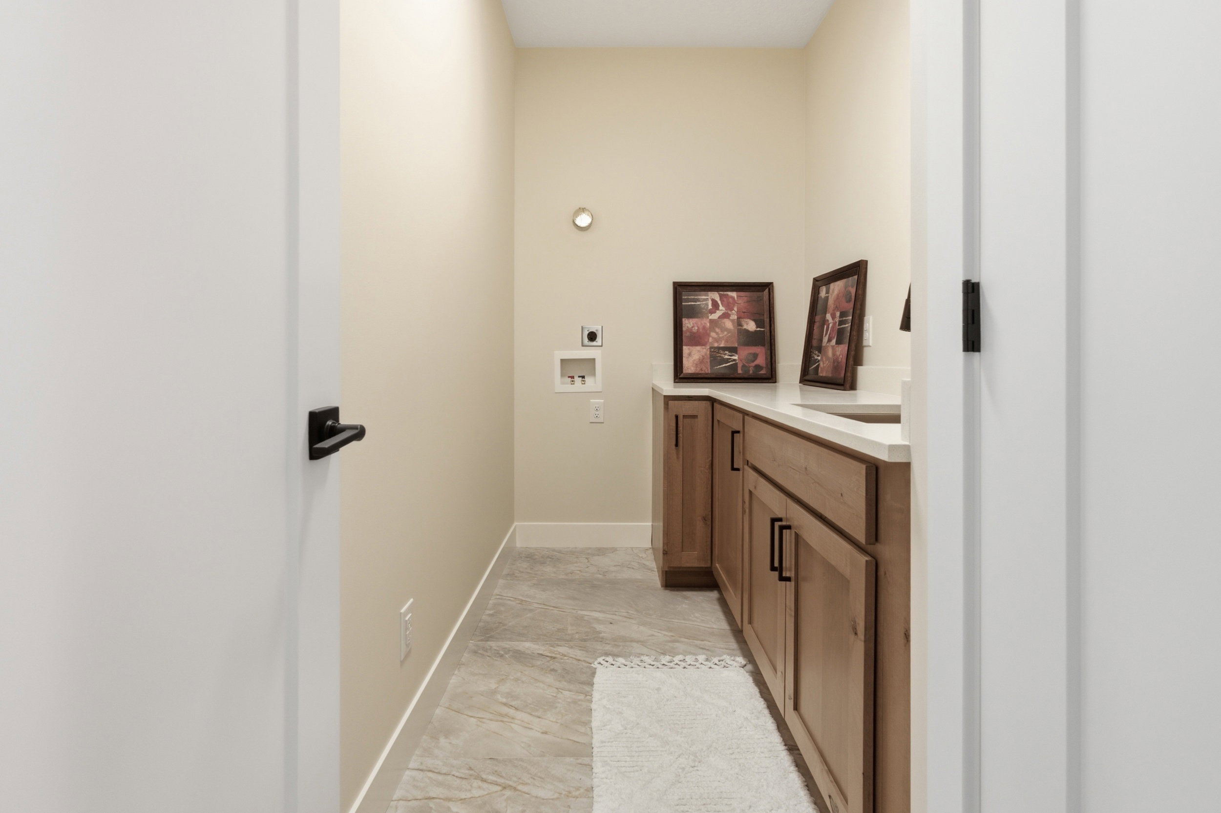 Dedicated utility room featuring wood-finish cabinetry, light-toned countertops, and tile flooring