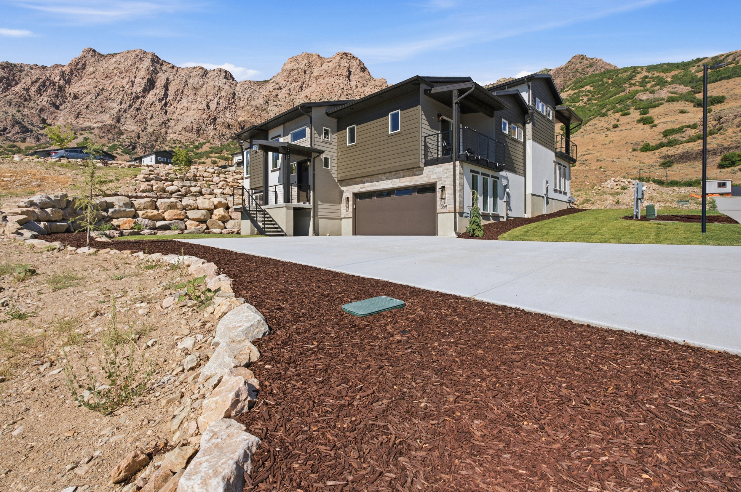 Modern multi-level residence featuring stone accent siding, dark wood-tone siding, and a two-car garage