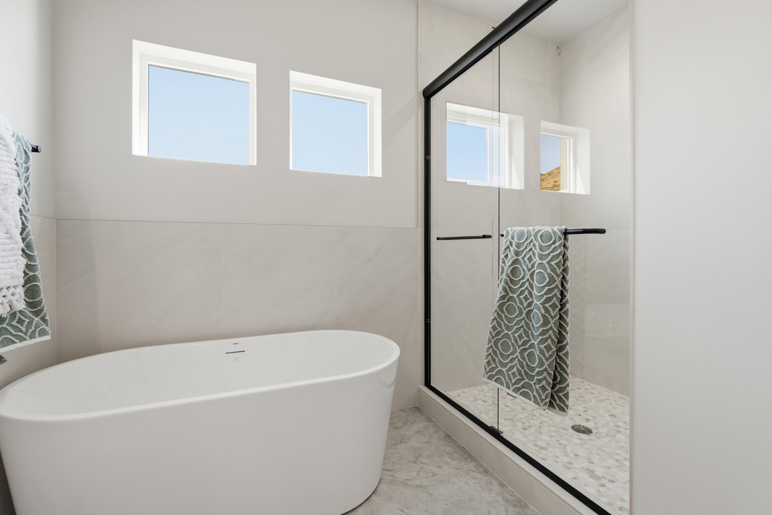 Freestanding soaking tub with a walk-in shower featuring a frameless glass enclosure and black trim