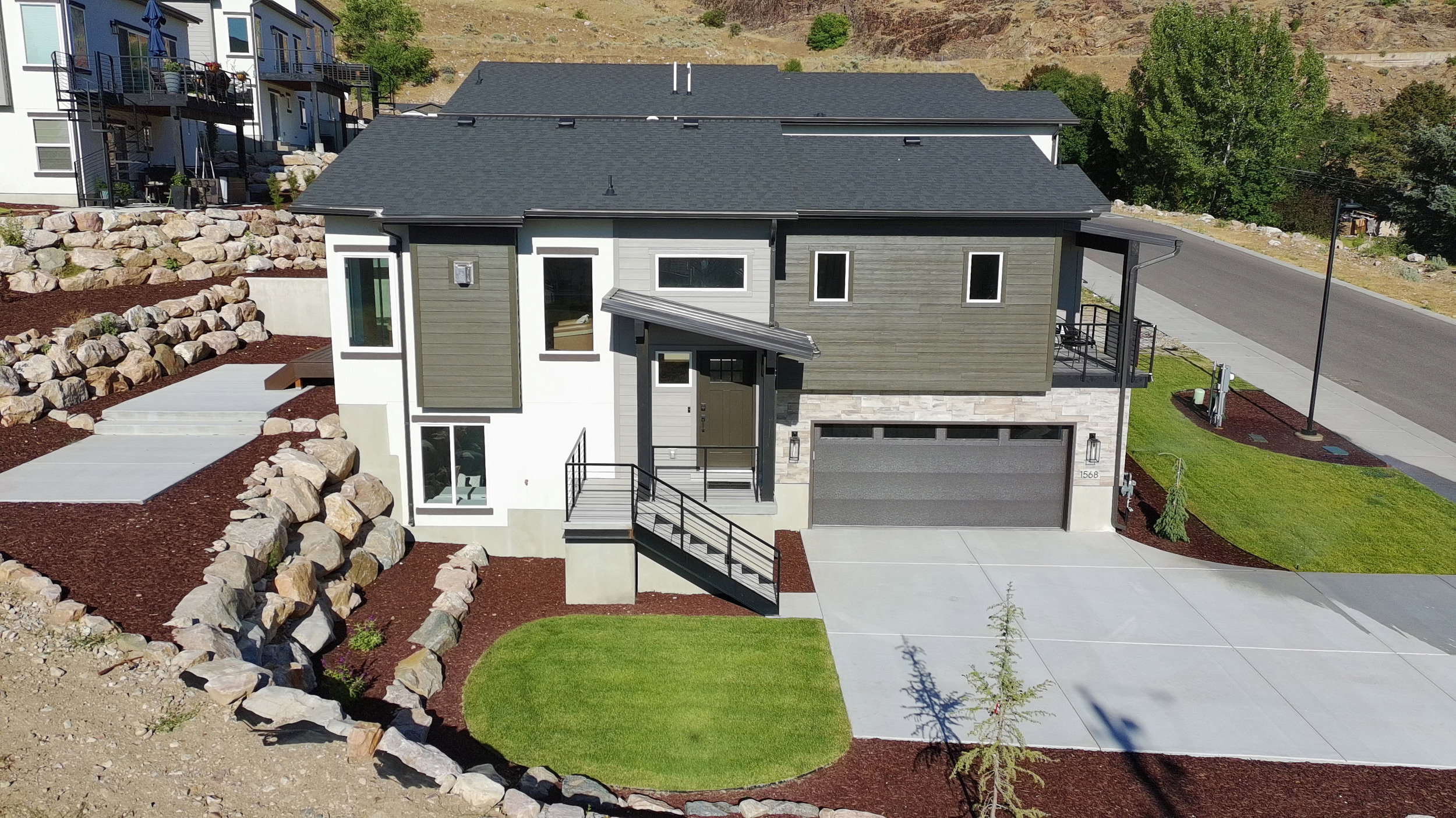 Modern multi-level residence featuring a dark gray roof, wood-look siding accents, and a concrete driveway