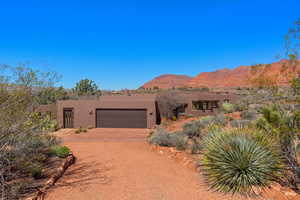 Adobe home with stucco siding, driveway, a mountain view, and an attached garage