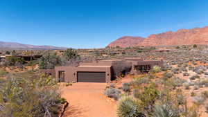 Adobe home featuring a mountain view, stucco siding, concrete driveway, a garage, and view of desert