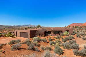 Pueblo-style home featuring a mountain view, driveway, stucco siding, and a garage