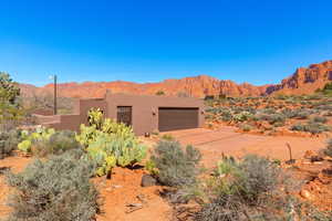 Pueblo-style home with a mountain view, stucco siding, driveway, and an attached garage