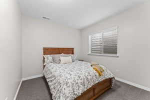 Bedroom featuring dark carpet and baseboards