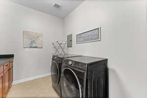Laundry room with separate washer and dryer, electric panel, a textured ceiling, and light tile patterned floors