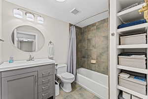 Bathroom with vanity, shower / bath combination with curtain, and stone finish flooring