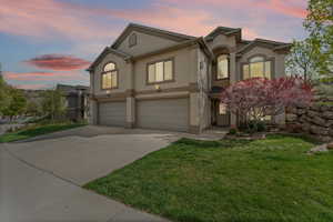 View of front of property featuring stucco siding, a garage, concrete driveway, and a front lawn
