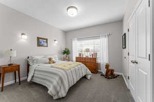 Carpeted bedroom with a closet and baseboards