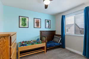 Carpeted bedroom featuring ceiling fan and a textured ceiling