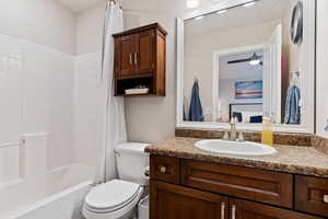 Full bathroom with vanity, shower / tub combo, and a ceiling fan