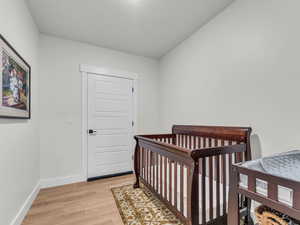 Bedroom with a nursery area, light wood-type flooring, and a closet