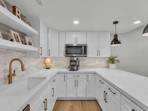 Kitchen with white cabinetry, light stone countertops, and open shelves
