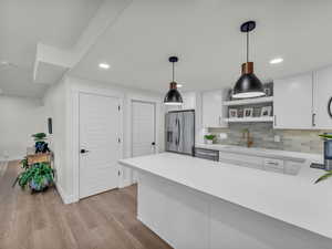Kitchen with white cabinetry, open shelves, stainless steel appliances, and decorative light fixtures