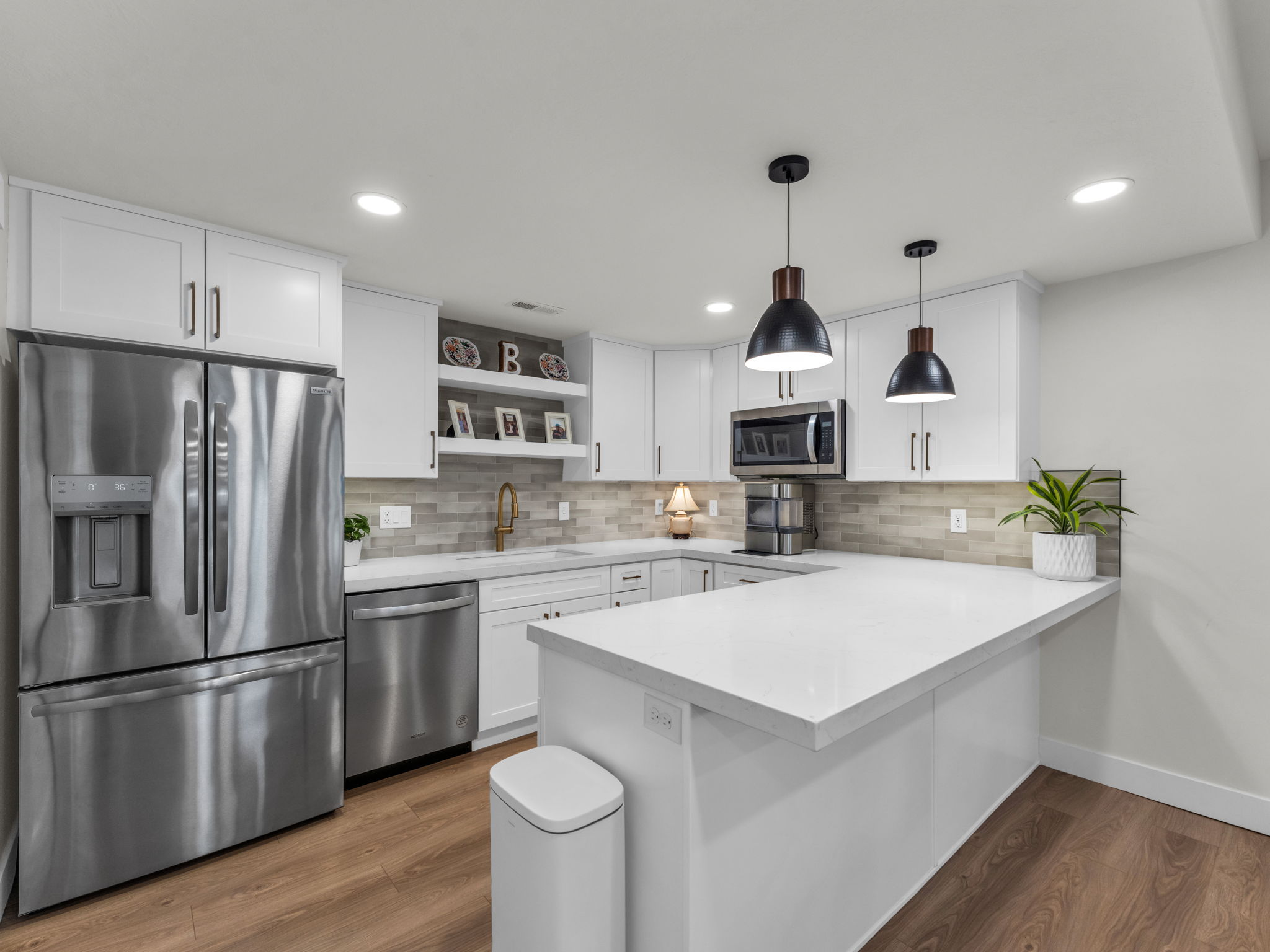 Kitchen with stainless steel appliances, open shelves, a peninsula, wood finished floors, and white cabinets