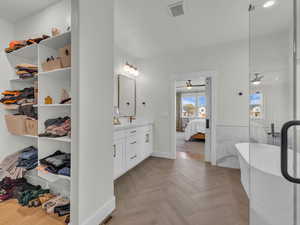 Bathroom with ensuite bath, double vanity, tile walls, a shower stall, and a soaking tub