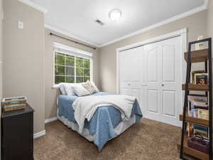 Bedroom featuring crown molding, a closet, and dark carpet