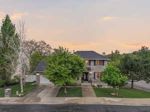View of front facade with a lawn, driveway, a garage, and brick siding