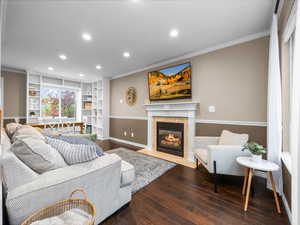 Living area featuring recessed lighting, wood-type flooring, crown molding, a premium fireplace, and built in shelves