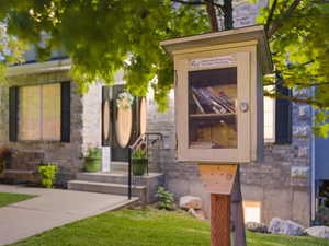 View of exterior entry with a lawn and stone siding