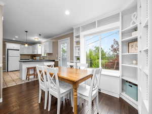 Dining room with ornamental molding, dark wood finished floors, and recessed lighting