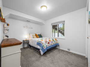 Bedroom featuring baseboards and dark carpet