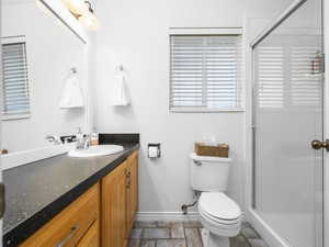 Full bath featuring stone tile flooring, a shower stall, and vanity