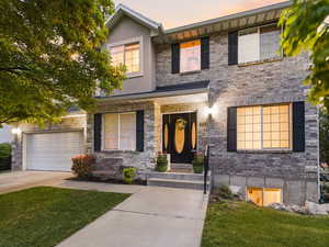 View of front facade featuring concrete driveway, covered porch, and a front yard