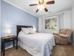 Bedroom featuring crown molding, dark carpet, and a ceiling fan