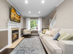 Living area with crown molding, dark wood-style floors, a tile fireplace, and recessed lighting
