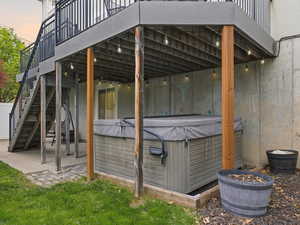 Patio terrace at dusk featuring a patio, a wooden deck, and a hot tub