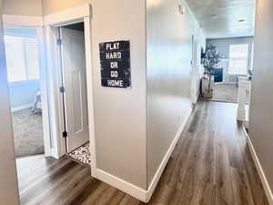 Hallway with dark wood-style flooring, a textured ceiling, and recessed lighting