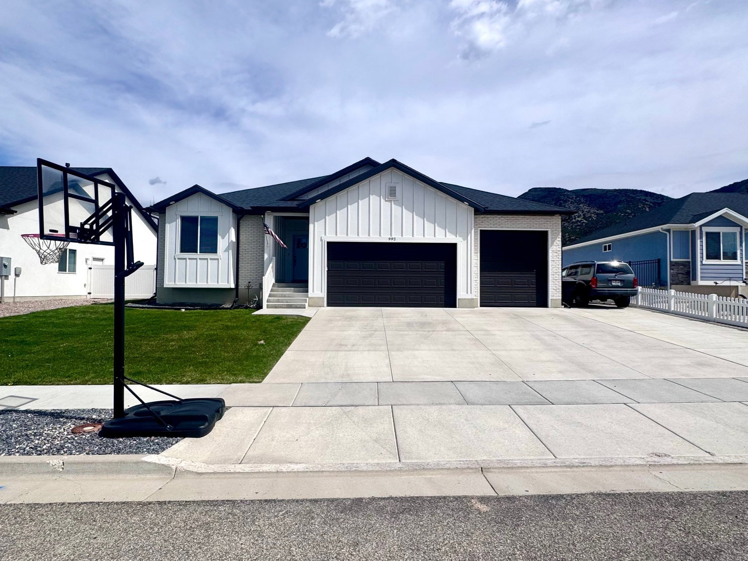Modern farmhouse with board and batten siding, an attached garage, driveway, and a front yard