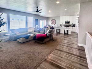 Living area with dark wood-type flooring, a textured ceiling, ceiling fan, and recessed lighting
