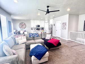 Living room featuring carpet flooring, ceiling fan, a textured ceiling, and recessed lighting