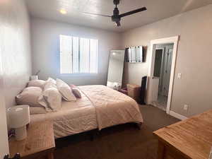 Bedroom with dark carpet, ceiling fan, and a textured ceiling
