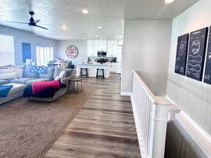 Living area featuring dark wood-style flooring, recessed lighting, a textured ceiling, and a ceiling fan