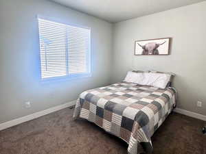 Bedroom with dark carpet and a textured ceiling