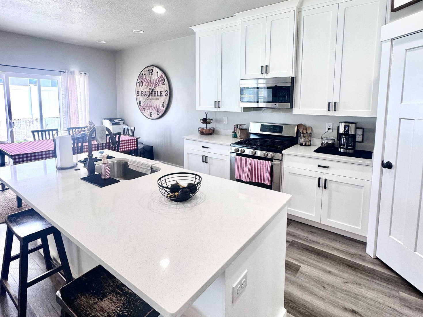 Kitchen featuring a kitchen breakfast bar, an island with sink, white cabinetry, stainless steel appliances, and a textured ceiling
